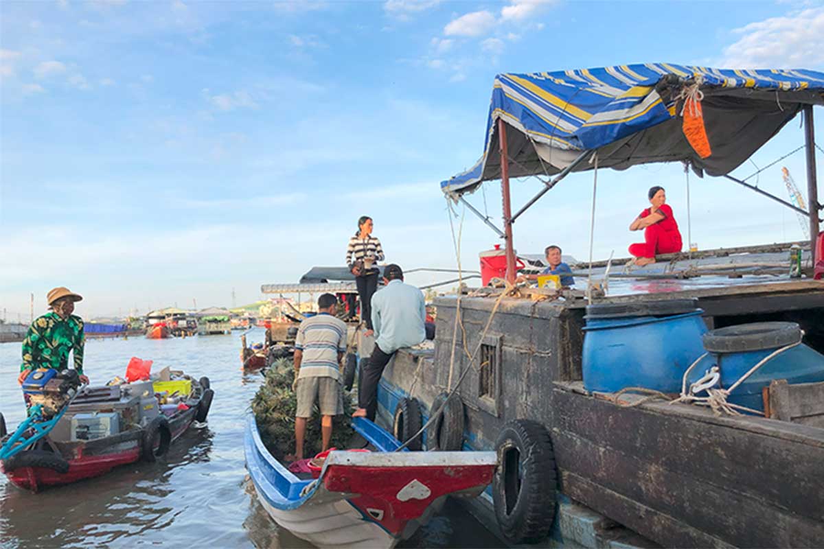 three boats with people on them trading goods