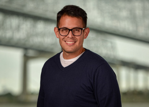 Photograph: Smiling man with glasses in a navy sweater.