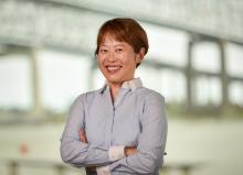 Smiling woman with short hair, crossed arms, wearing a blue striped shirt.
