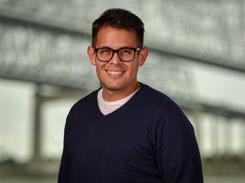 Photograph: Smiling man with glasses in a navy sweater.